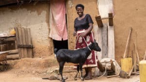 Lovance, a VSLA member, excitedly shows the goat she bought by saving with the VSLA.